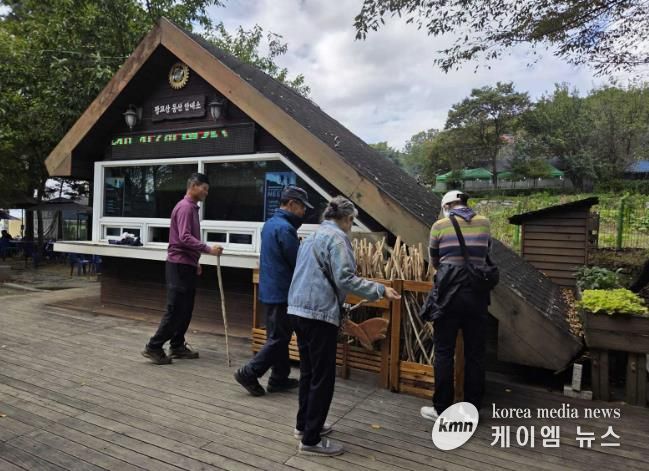 등산객들이 광교산 등산 안내소 앞에 있는 지팡이를 고르고 있다.