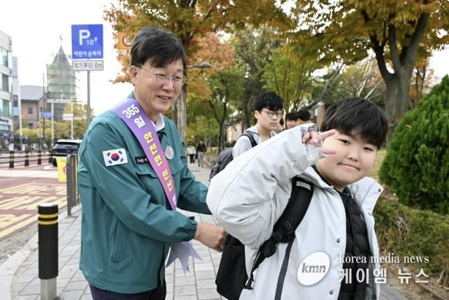 이민근 안산시장(사진 왼쪽)이 학현초등학교 앞에서 ‘스쿨존 어린이 교통안전 캠페인’을 진행하며 등교하는 어린이의 가방에 '홍이 키링'을 달아주고 있다.