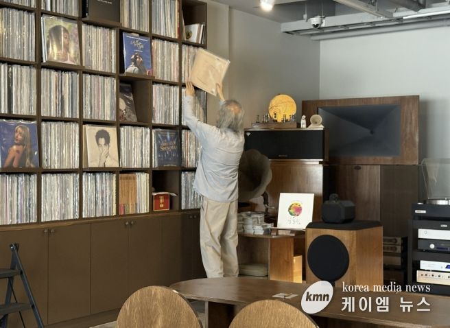 음악감상실 온 주인장이 신청곡 LP를 찾고 있다.