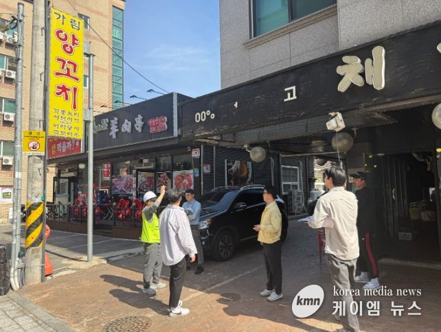 정명조 건축과장과 관계자들이 도로변 상가 간판의 안전 상태를 확인하며 현장점검을 하고 있다.